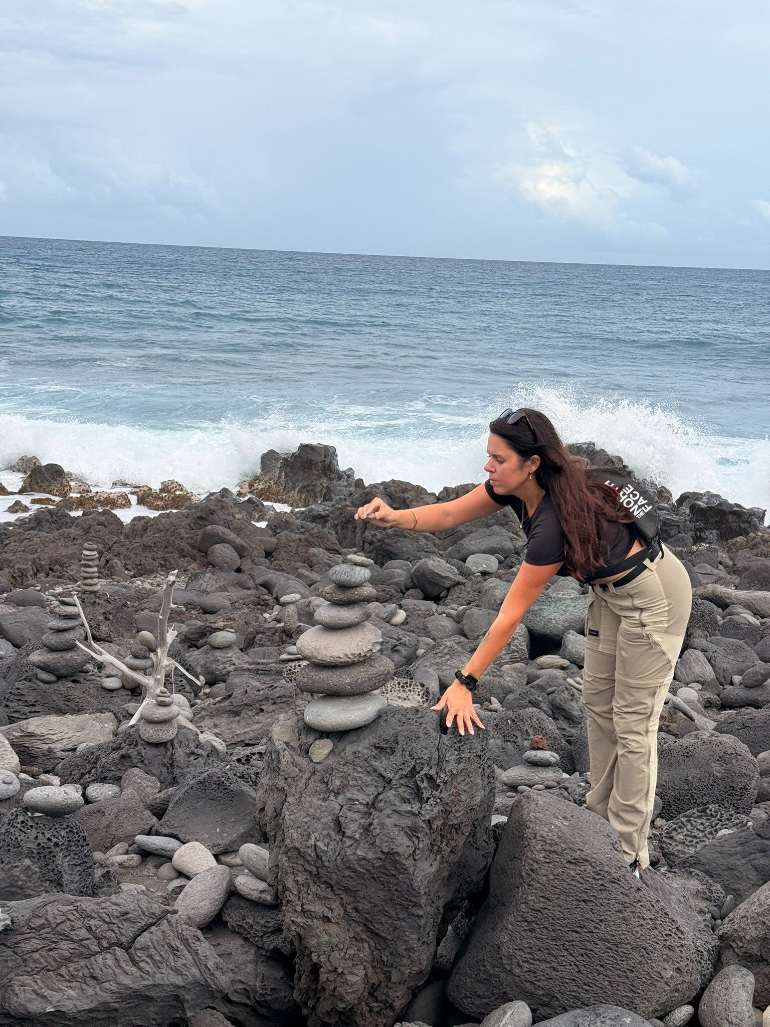 Femme posant un galet en équilibre sur un cairn le long du Vortex à Étang-Salé, La Réunion