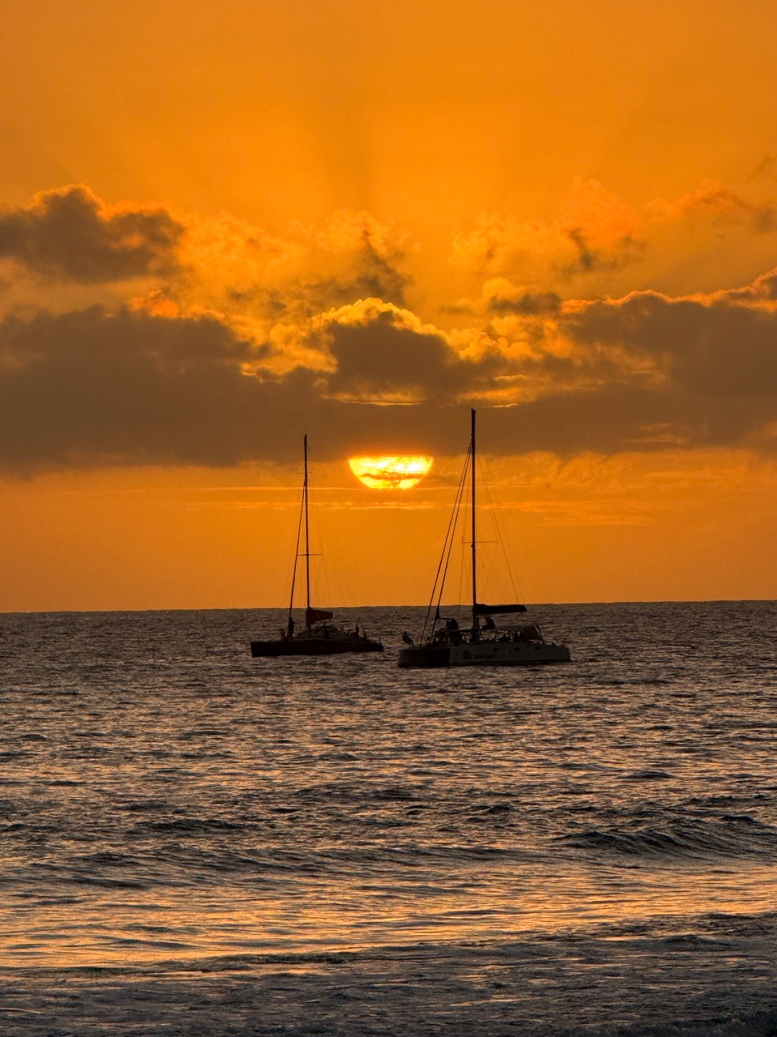 Coucher de soleil sur l’océan Indien derrière deux catamarans au large de Saint-Gilles, La Réunion
